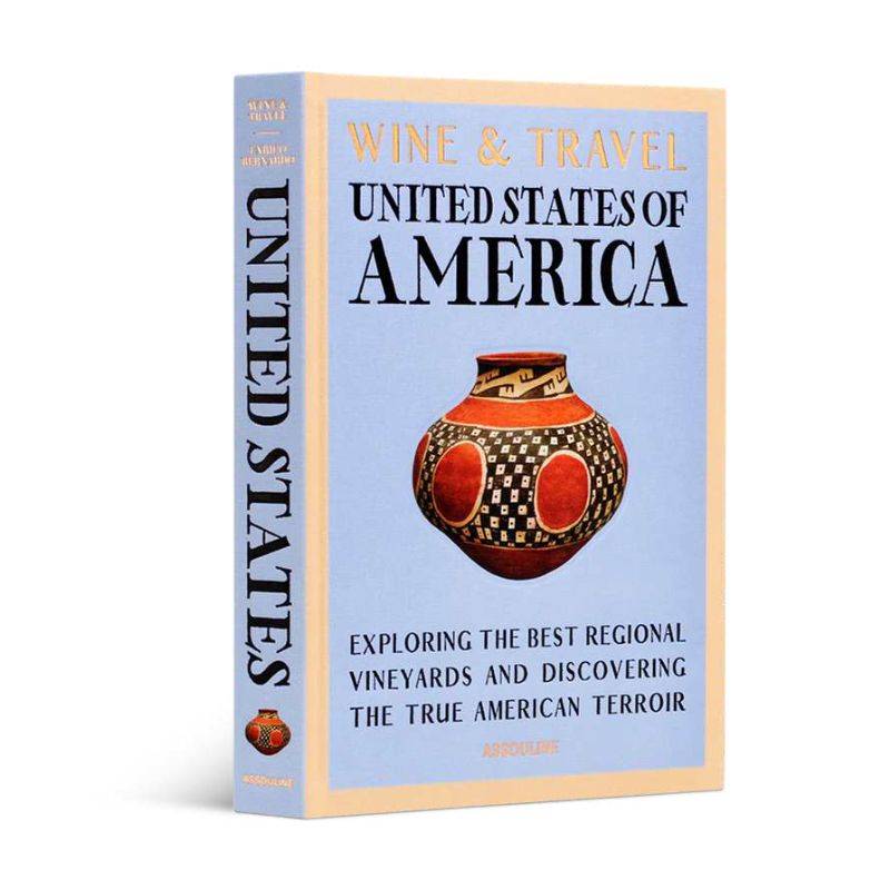 Livro Wine & Travel United States of America Assouline com capa dura sobre mesa de centro de madeira, ao lado de taça de vinh