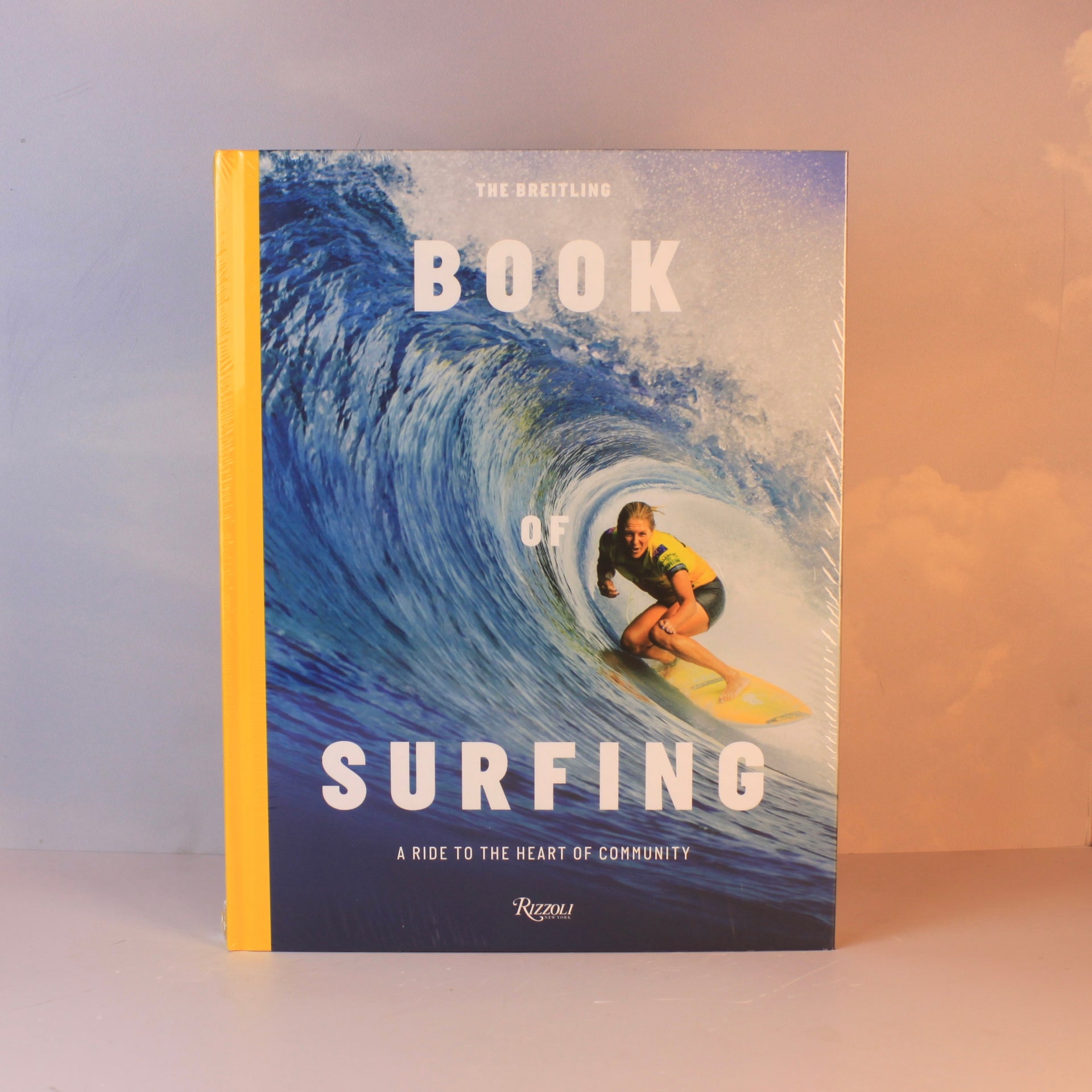Livro The Breitling Book of Surfing Rizzoli com capa dura sobre mesa de centro de madeira em living com prancha de surfe e de