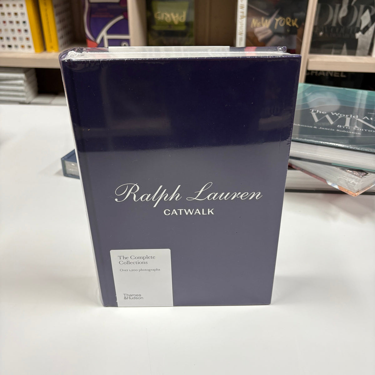 Livro Ralph Lauren Catwalk com capa dura sobre mesa de centro de madeira nobre em sala de estar elegante com poltrona de cour