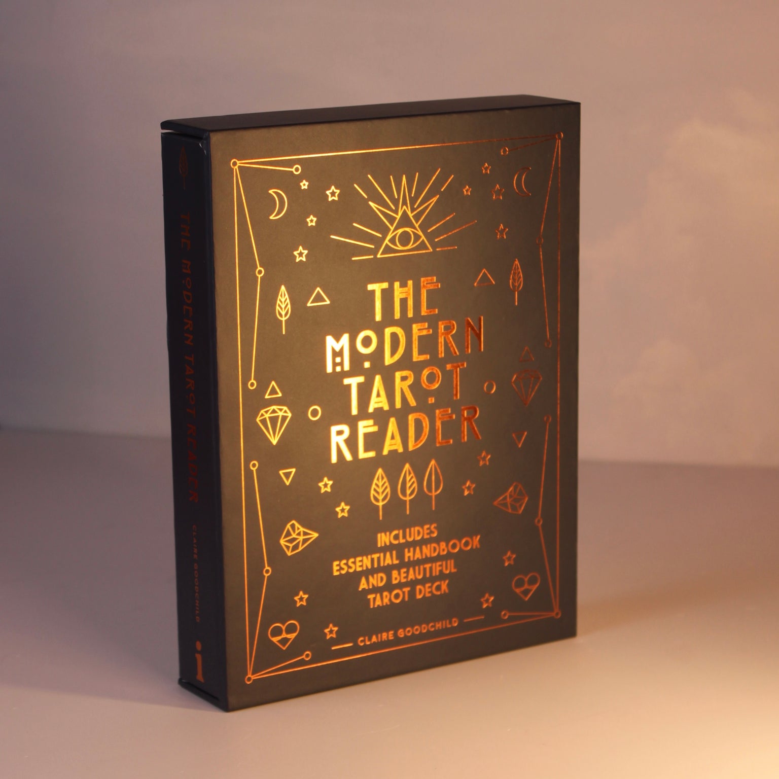 Kit The Modern Tarot Reader com 78 cartas de tarô e livro guia em inglês sobre mesa de madeira escura ao lado de cristais e v