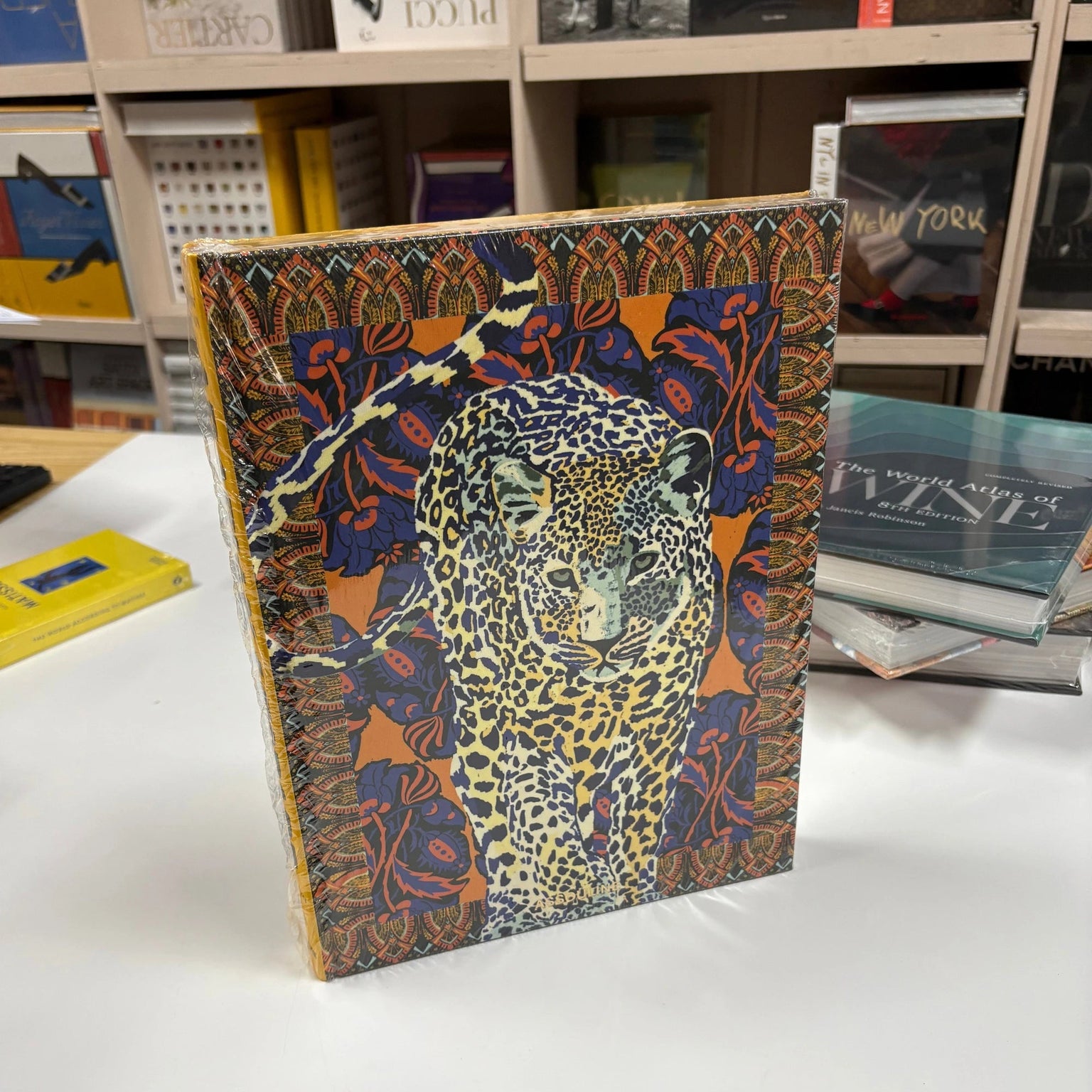 Livro Arabian Leopard Assouline com capa dura em tons terrosos sobre mesa de centro de madeira nobre, ao lado de uma escultur