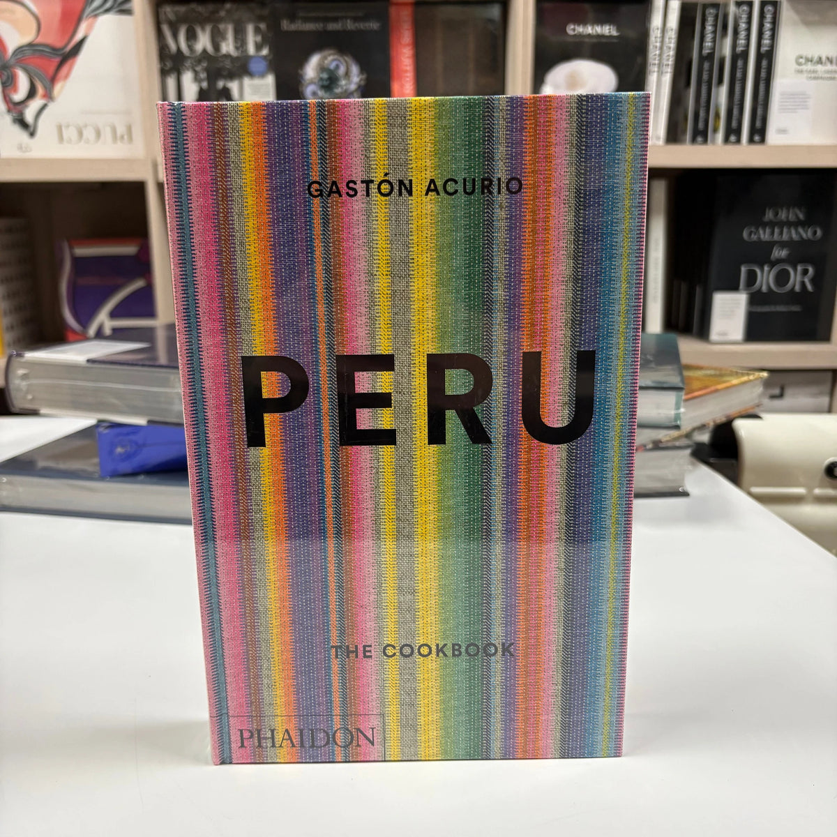 Livro Peru The Cookbook Phaidon Press com capa dura colorida sobre mesa de centro de madeira ao lado de uma xícara de café e